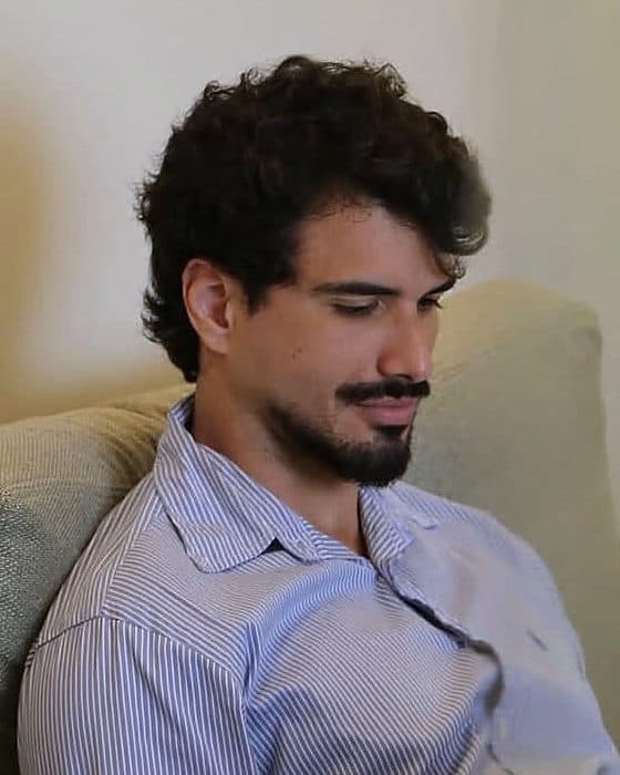 Italo Ito, sócio da ávera, sentado no sofá olhando para o notebook.