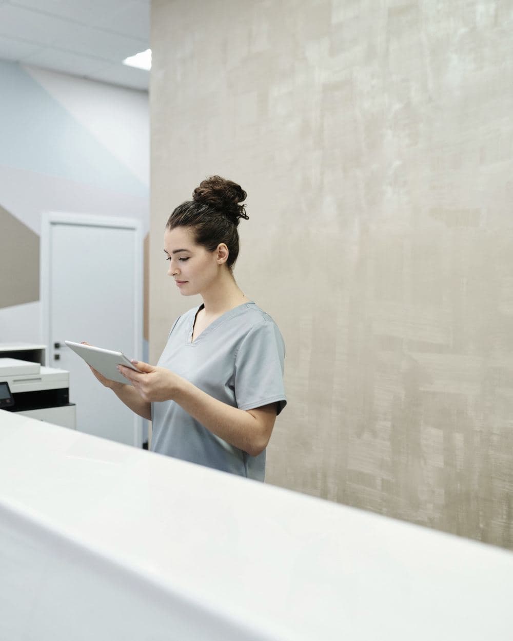 Profissional de saúde consultando um tablet na recepção de uma clínica.
